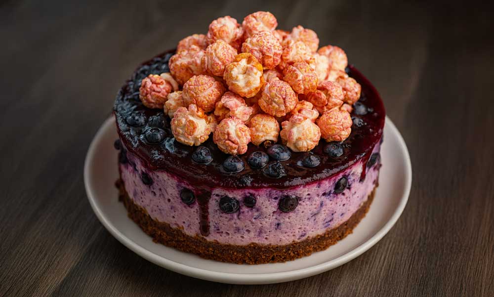 Delicious blueberry cheesecake topped with Pop Yum popcorn, perfect for the ultimate dessert recipe.