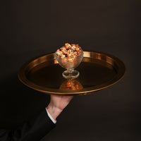 Salted caramel popcorn, drizzled with vegan Belgian chocolate, pictured on a gold metal tray.