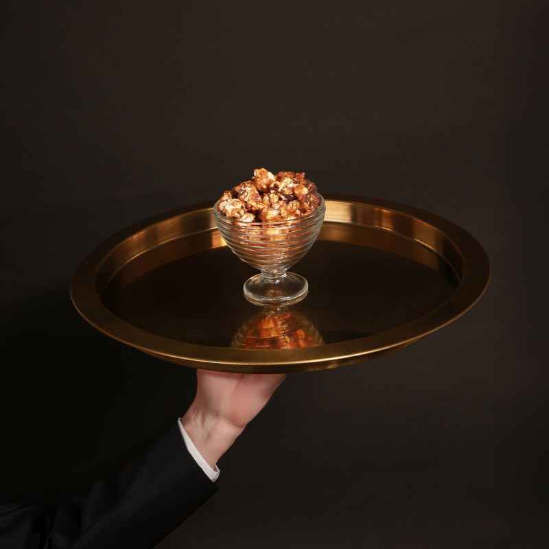 Salted caramel popcorn, drizzled with vegan Belgian chocolate, pictured on a gold metal tray.
