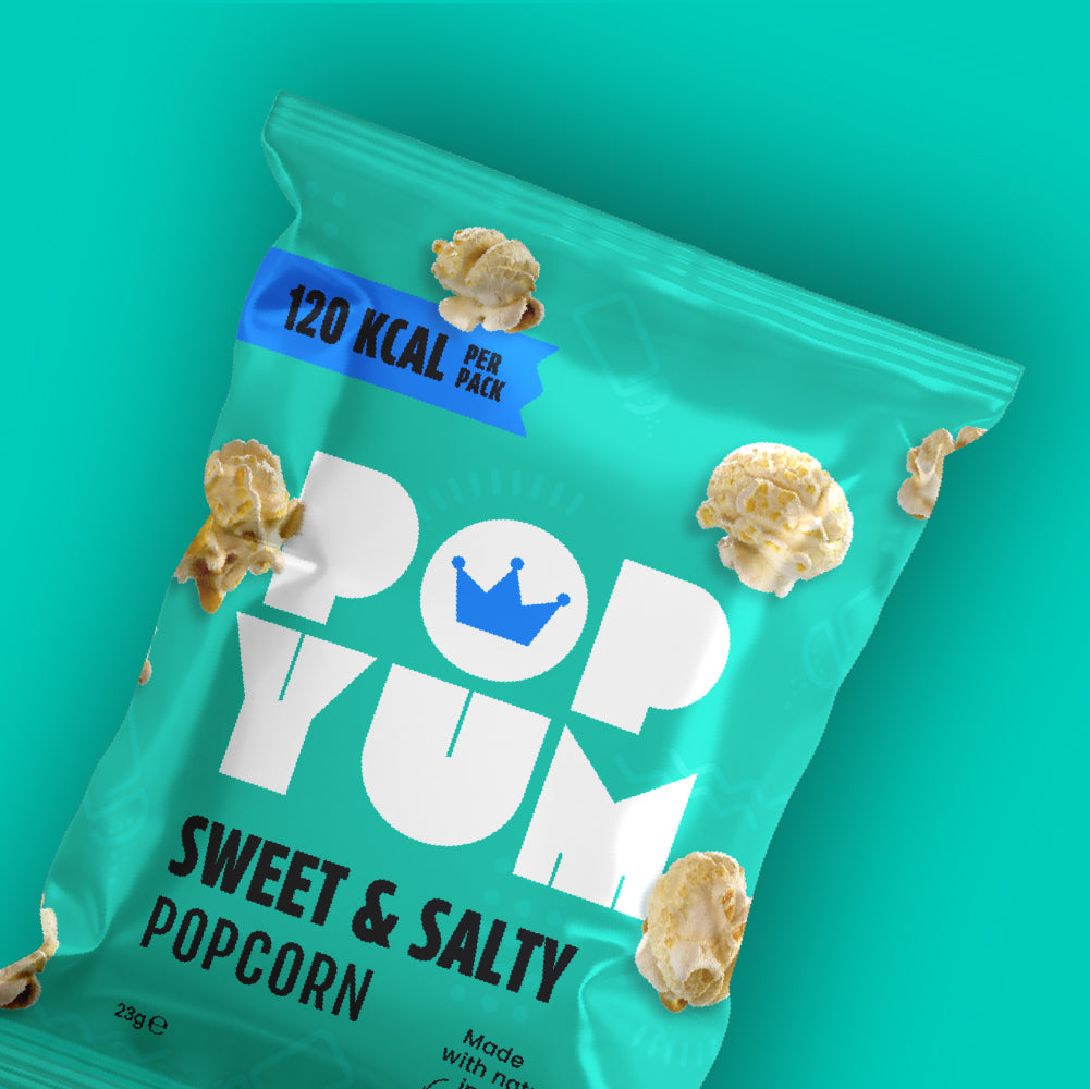 Green bag of Pop Yum sweet and salty popcorn with popcorn kernels on a teal background. 120 kcal per pack is also displayed.