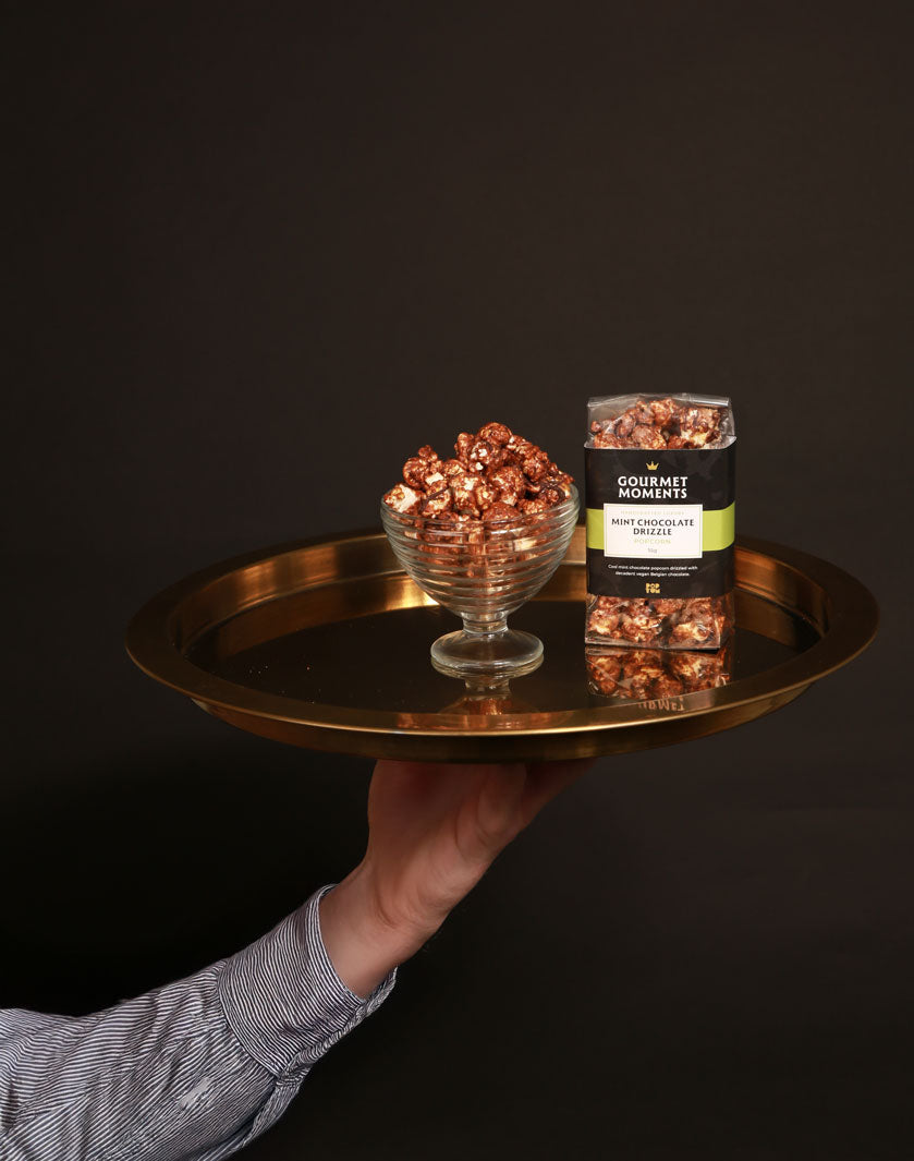 Gourmet Moments luxury popcorn, held on a gold tray, by a man dressed in a smart shirt.