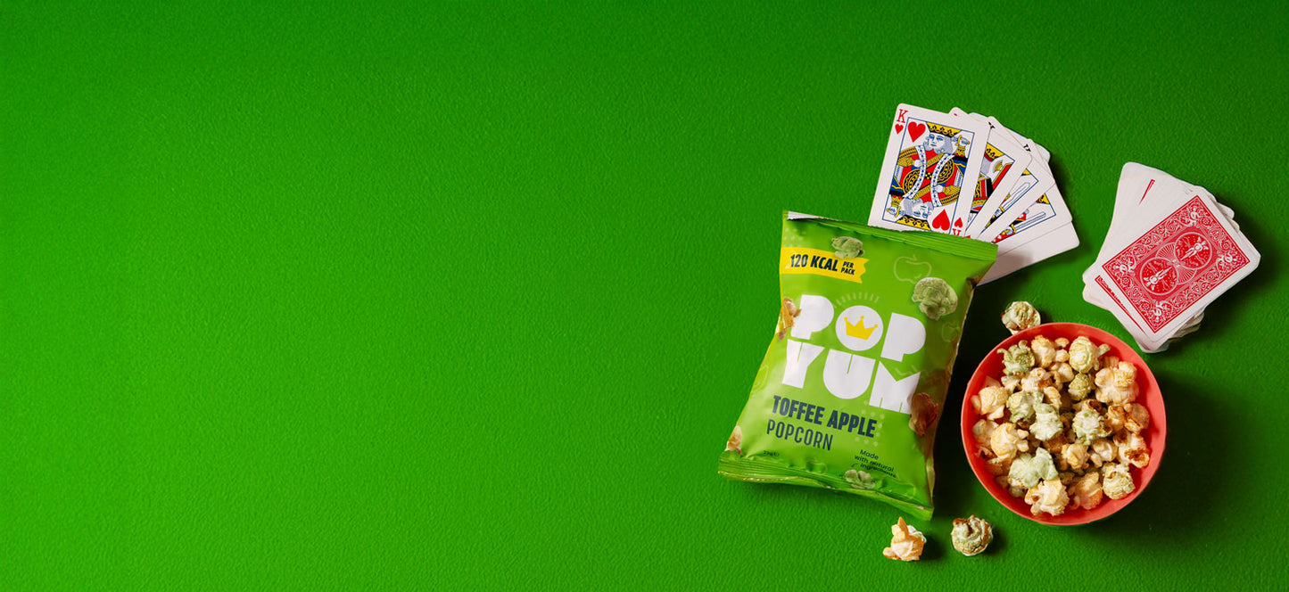 Popcorn packet, bowl of popcorn, and playing cards on a green poker table background.