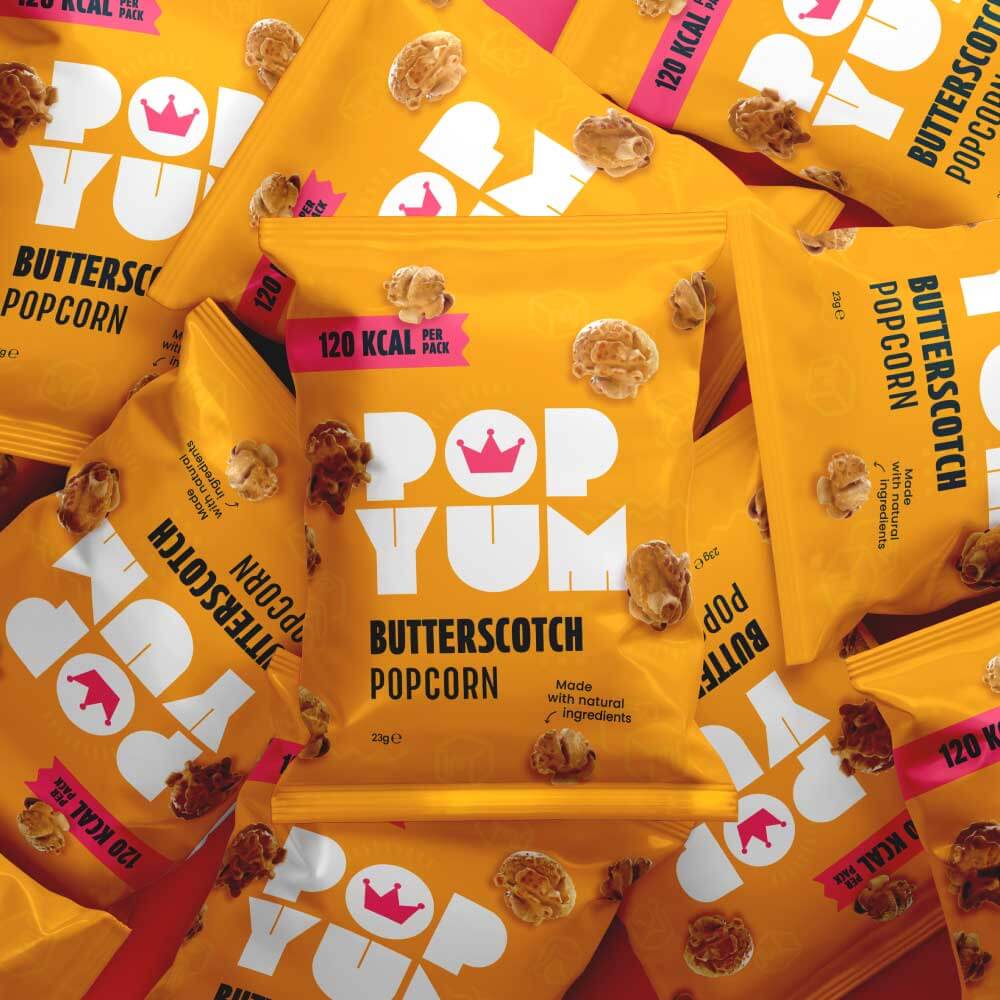 A pile of Pop Yum vegan & gluten-free butterscotch popcorn packets with visible branding and nutritional information.