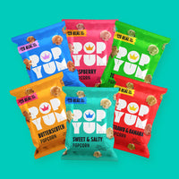 Pop Yum vegan popcorn packets on a blue background. Flavours include butterscotch, sweet and salty, toffee apple & more.