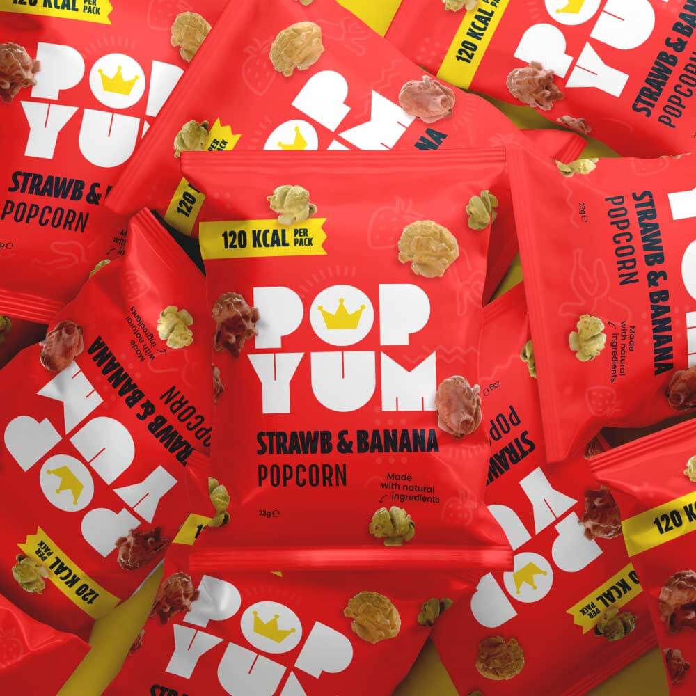 Red 'Pop Yum' strawberry and banana popcorn packets, made with natural ingredients on a yellow background.