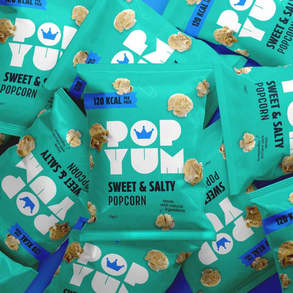 Multiple bags of Pop Yum sweet & salty popcorn with visible branding and low-calorie snack nutritional information.