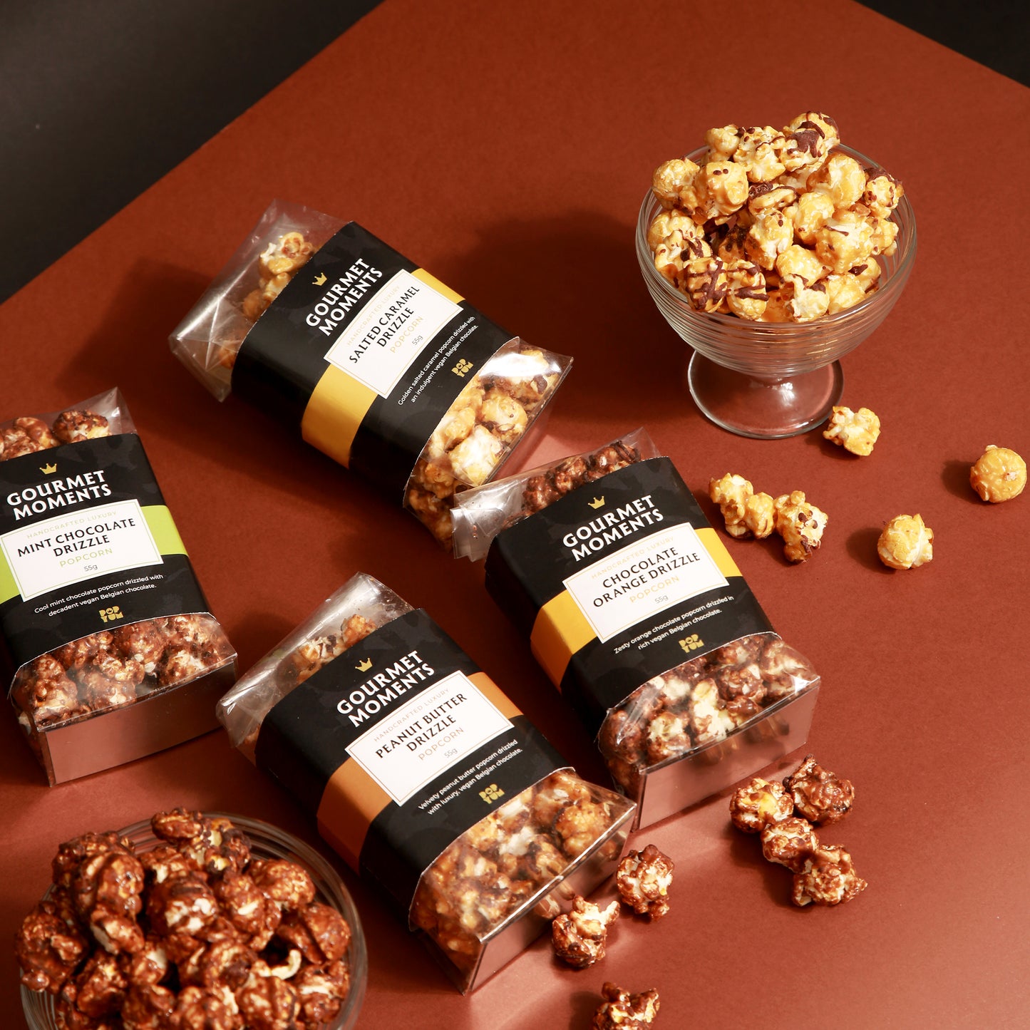 Vegan Belgian Chocolate drizzled popcorn hamper featuring 7 refined flavours in elegant packaging with popcorn in a bowl.