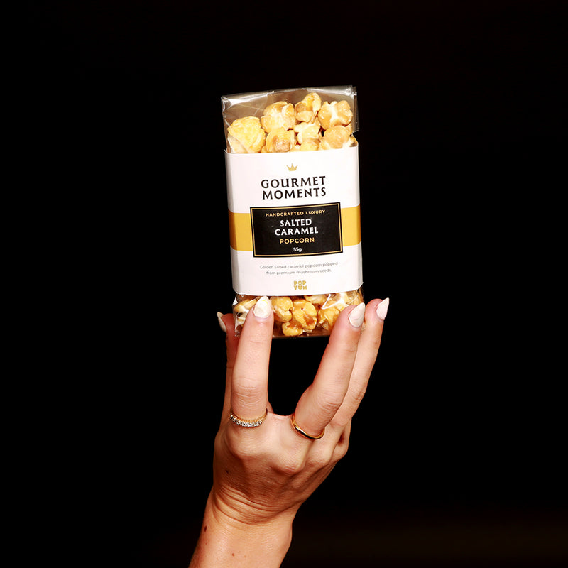 Vegan Salted Caramel Popcorn in a packet held by a hand for Gourmet Moments.